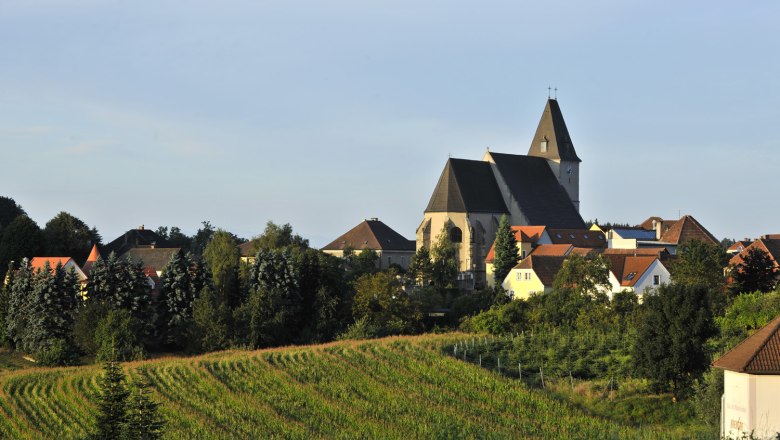 Landscape with church and village in the background, surrounded by fields and trees.