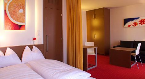 Hotel room with double bed, red carpet and modern furnishings.