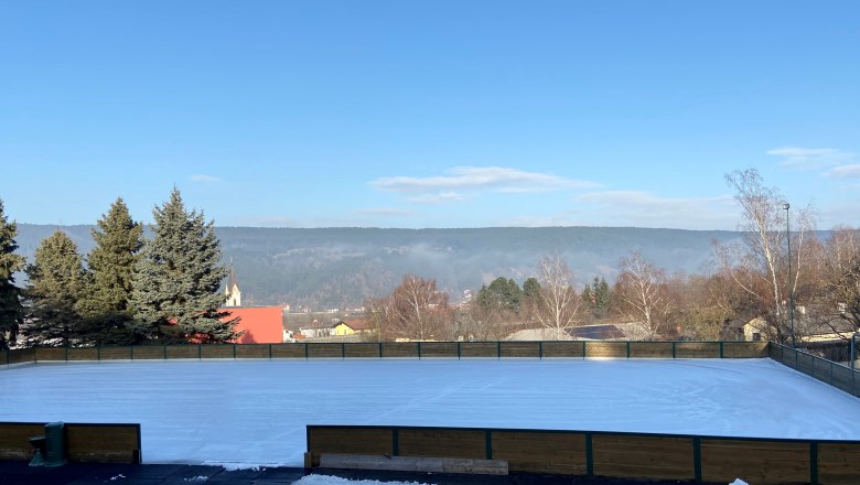 Ice rink with surrounding landscape and church in the background.