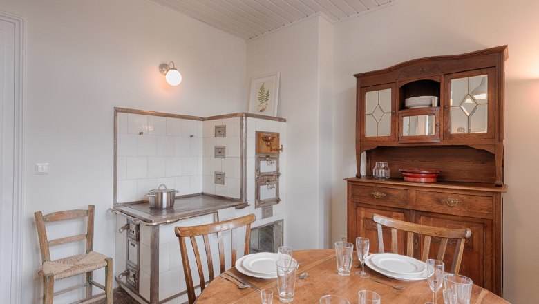 Vintage kitchen with wooden cupboard, old stove and laid table.