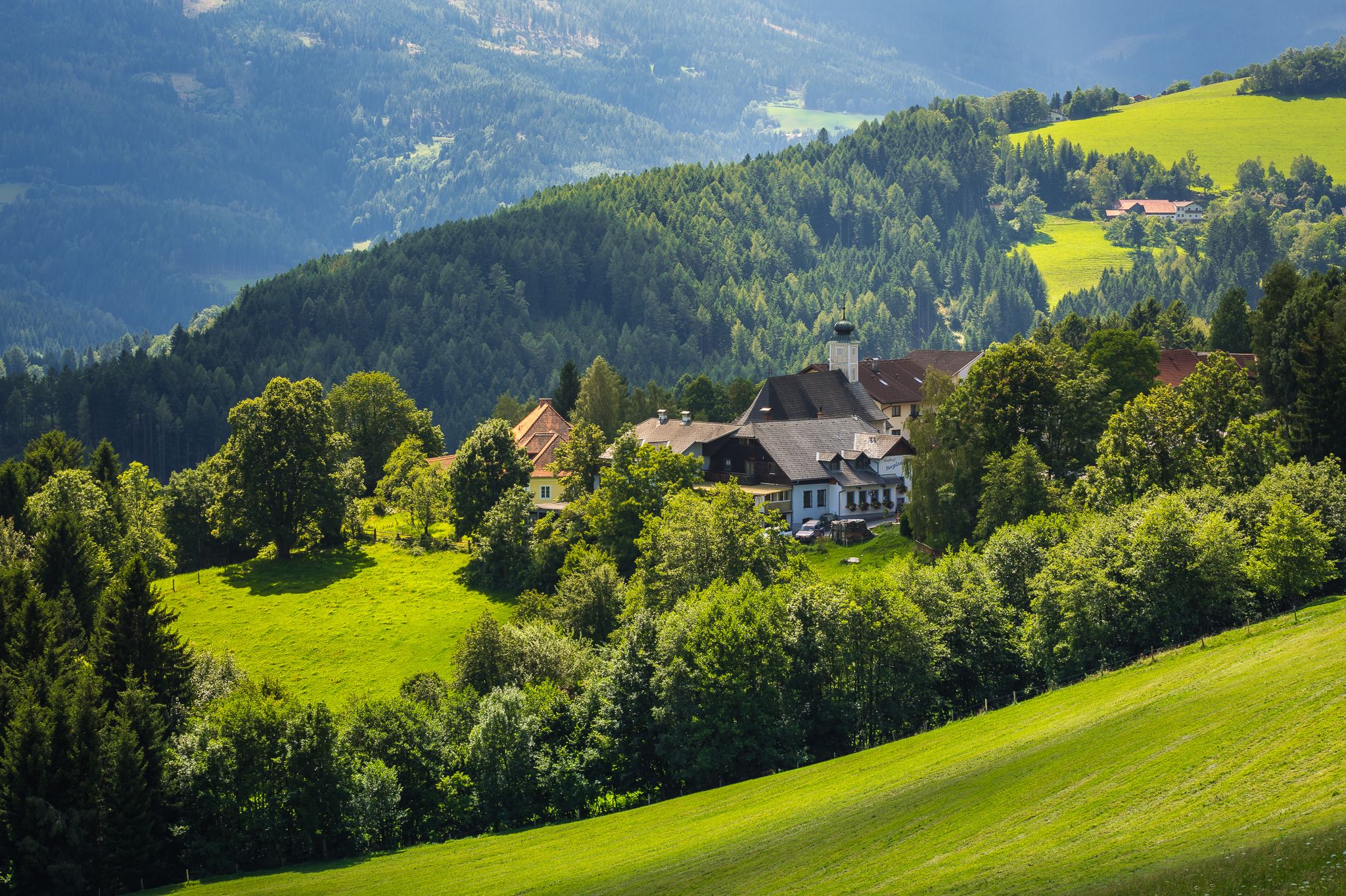 Rural landscape with houses and green hills.
