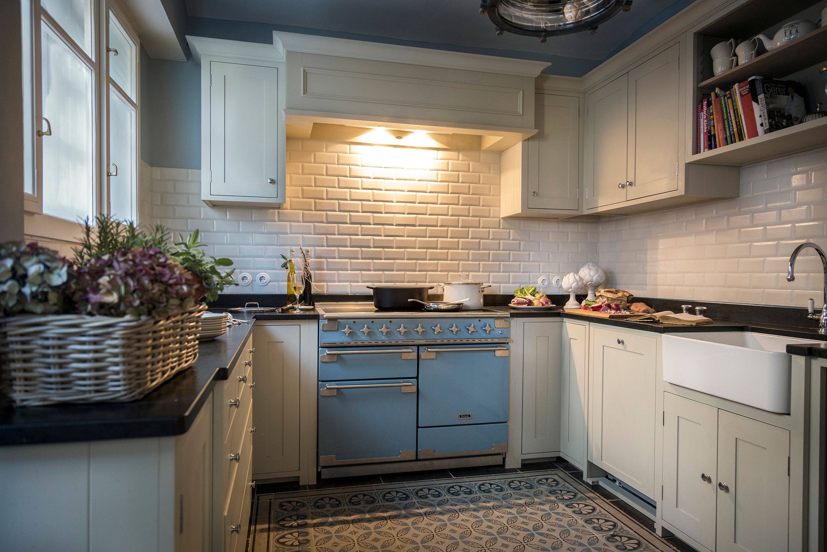 Elegant kitchen with blue oven, white cupboards and tiles.