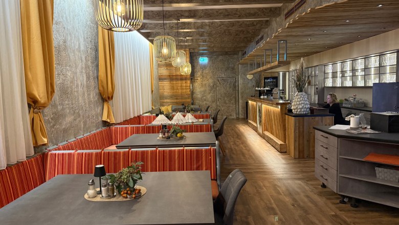 Interior view of a stylish restaurant with wooden elements and modern lighting.