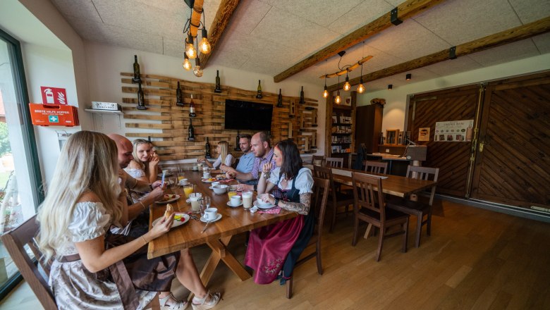 Group of people in traditional dress sitting at a table in a rustic room.