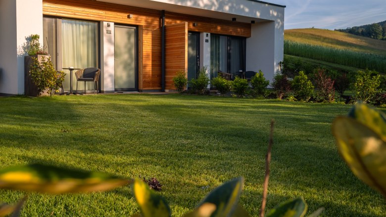 Modern building with wooden cladding and terrace in a green landscape.