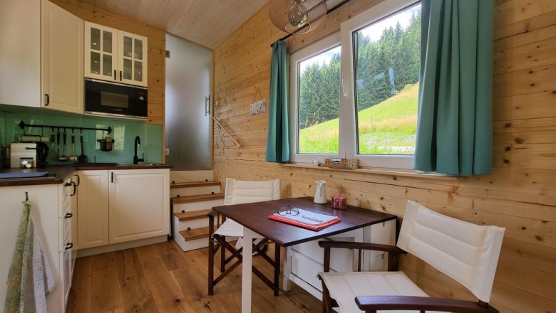 Small kitchen with dining area and window with view of meadow and forest.