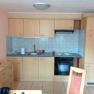 Small kitchen with wooden cupboards, sink, stove and tiled splashback.