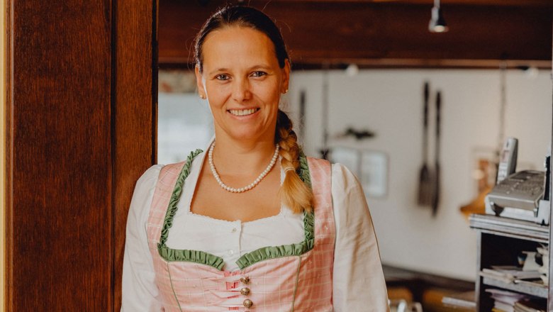 Woman in traditional costume smiling in a restaurant.