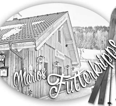 Black and white picture of a wooden house with the inscription 'Marios Futterkrippe'.