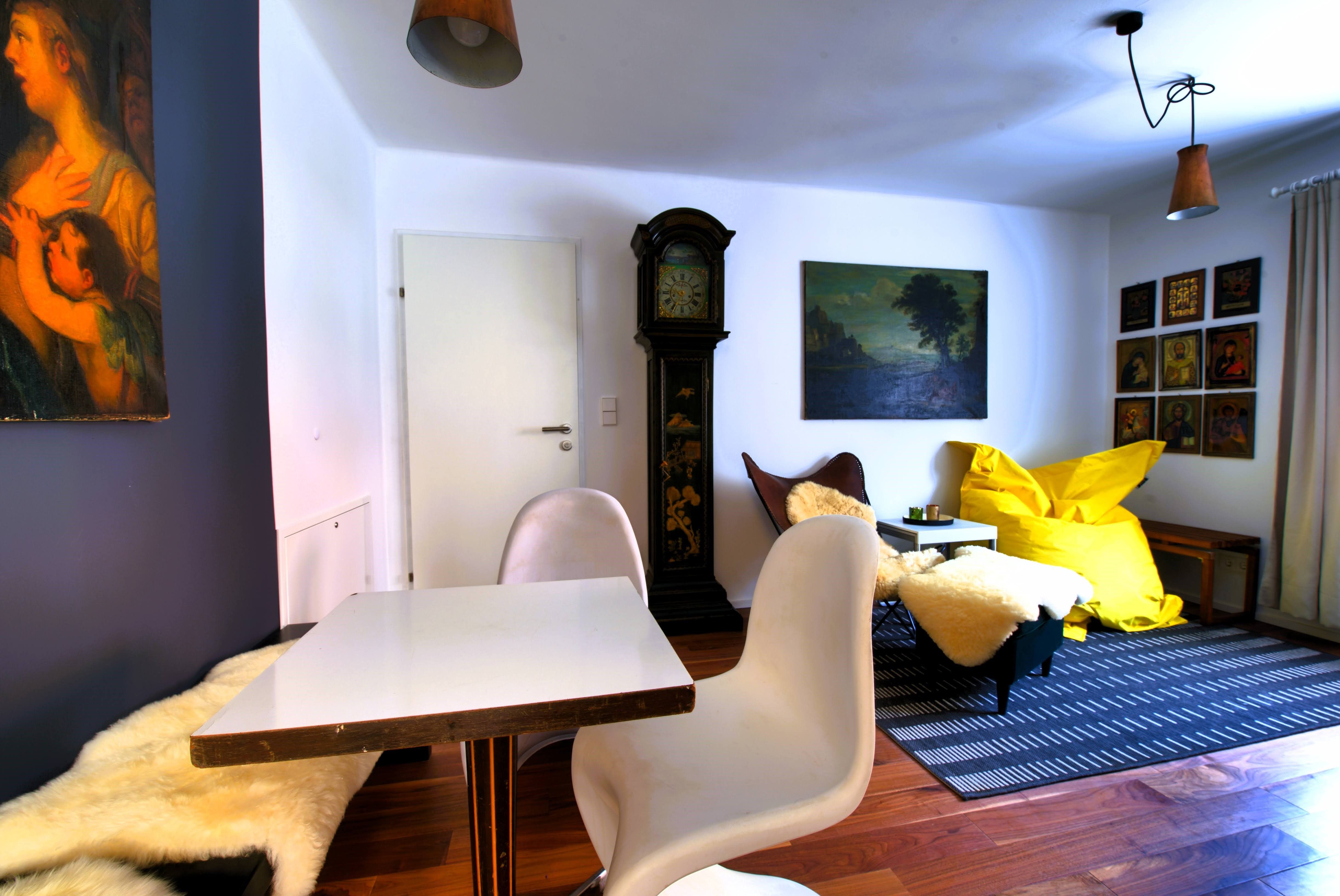 Living room with table, chairs, grandfather clock, paintings and yellow beanbag.