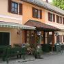 Entrance to a traditional inn with an orange façade and green wooden furniture outside.