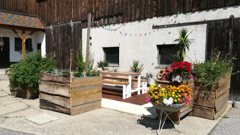Vacation at the Jauerling_Im Hof, © Romana Wiener A courtyard with wooden benches, flower boxes and colorful fairy lights.