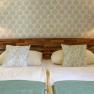 Cozy room with double bed, patterned wallpaper, wall lamps, bedside tables and pillows.