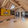 Interior view of a modern loft with wooden beams, large table and shelves.
