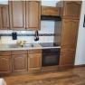Kitchen with wooden cupboards, stove and sink.