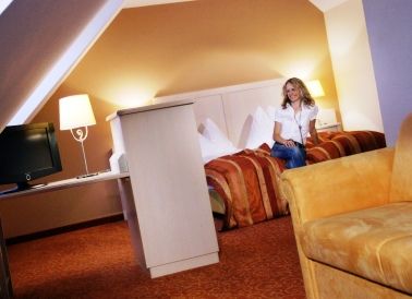 Woman sitting on a bed in a cozy hotel room with warm colors.