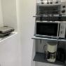 Kitchen shelf with toaster, microwave, coffee machine and kettle.