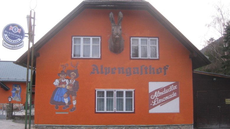 Rauraklalm, © Rauraklalm, Foto Andrea Illek Orange-painted building with the inscription 'Alpengasthof', wall painting of dancing couple and Almdudler advertisement.