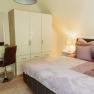 Bedroom with double bed, closet, dressing table and lamp.