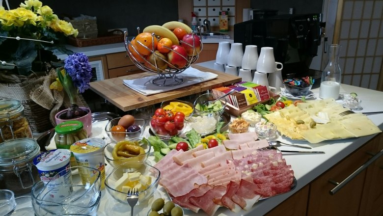 A rich breakfast buffet with cold cuts, cheese, fruit, vegetables and yogurt.