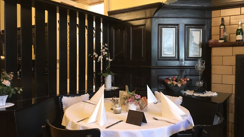 A cozy table in a traditional restaurant with dark wood paneling and decorative flowers.