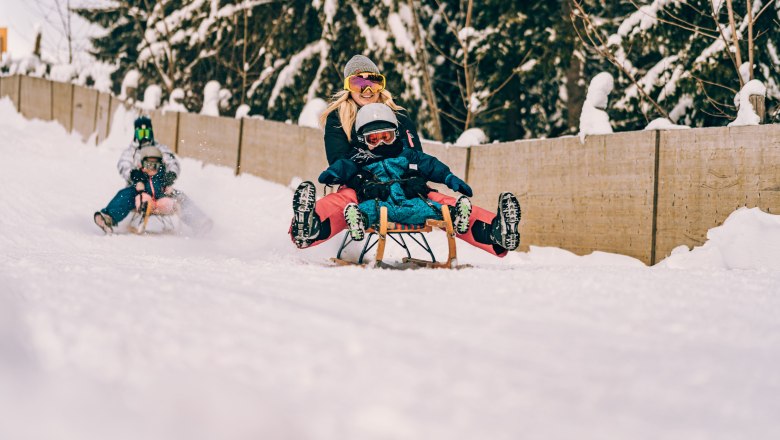 People tobogganing on a snow-covered run on the Semmering Hirschenkogel.