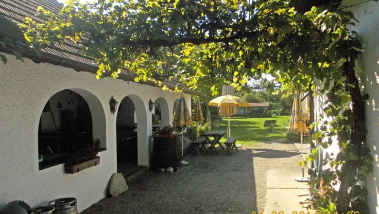 A cozy inn with white arches, a green pergola and yellow parasols in the garden.