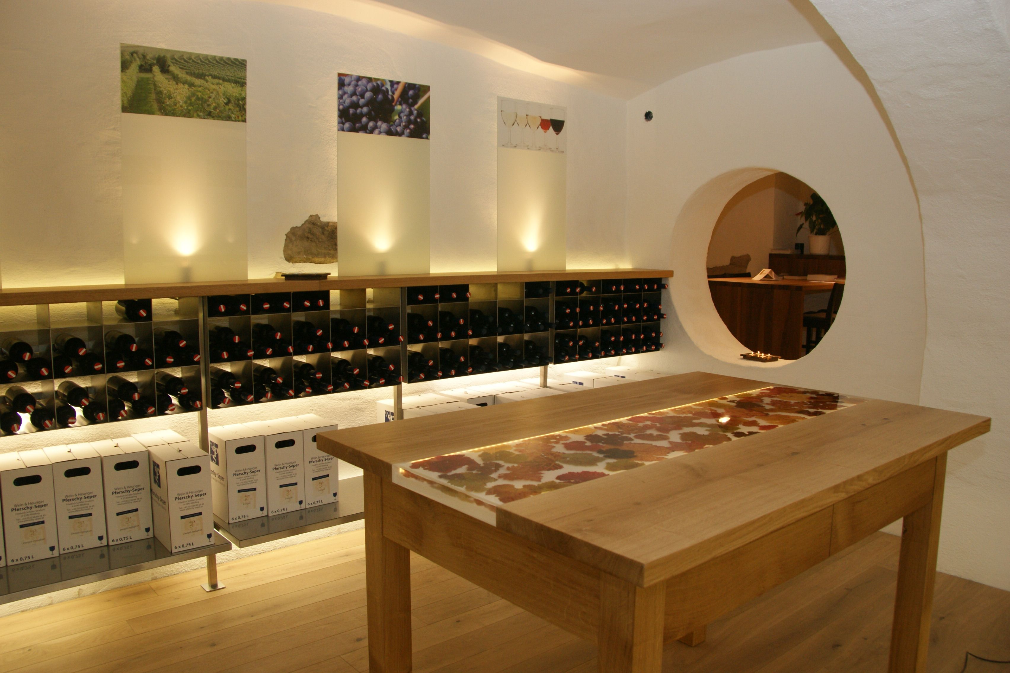 Wine cellar with shelves full of wine bottles and a wooden table in the middle.