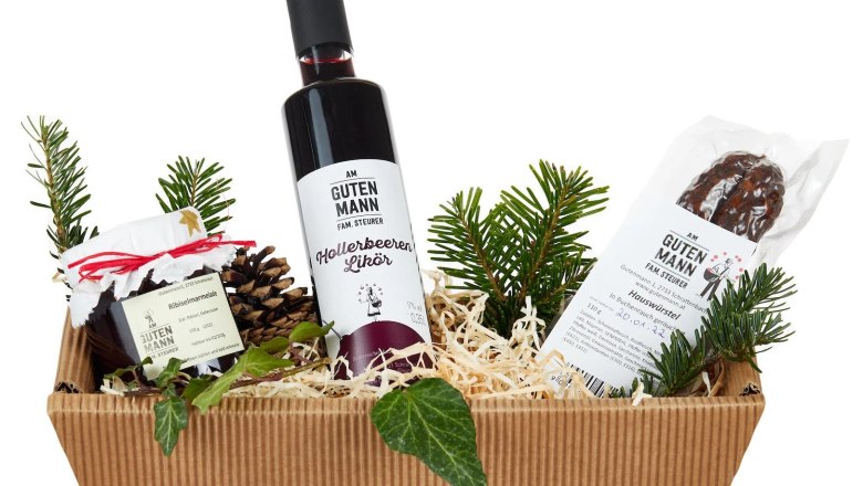 Gift basket with liqueur, jam and sausage, decorated with fir branches.