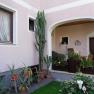 Inner courtyard with a view of a pink façade and many potted plants and windows.