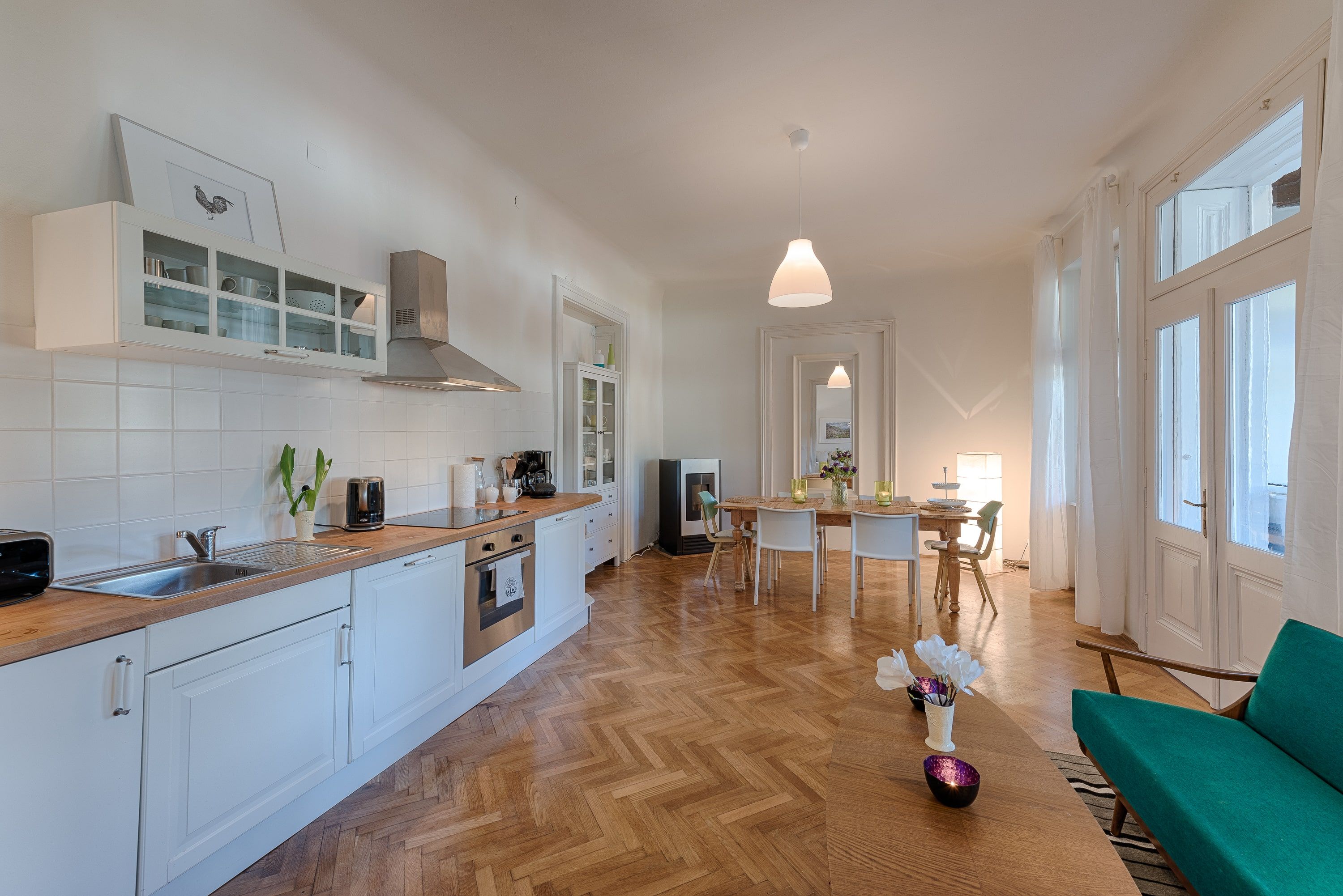 Modern kitchen with dining table, white cupboards and wooden floor.