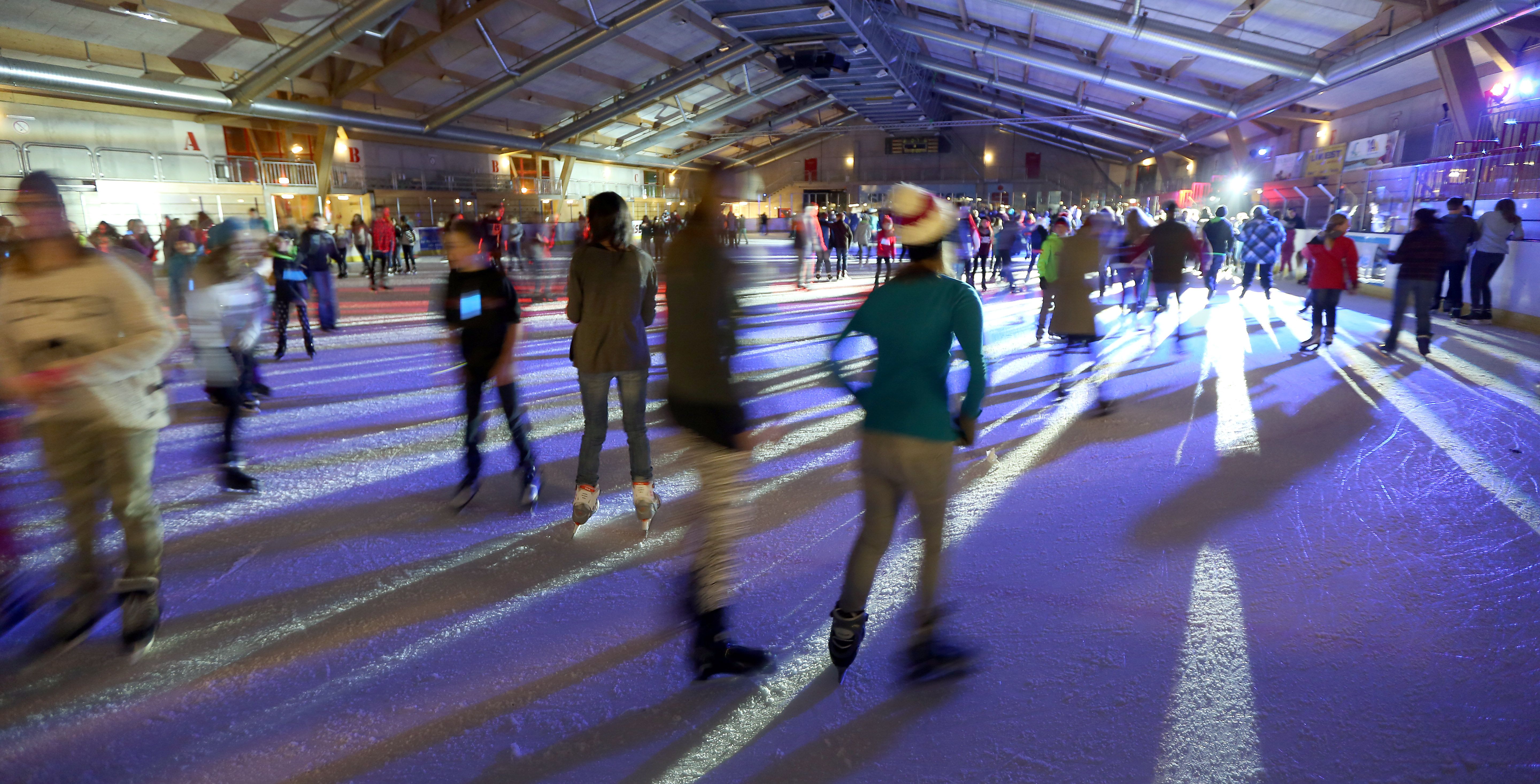 People ice skating in an illuminated ice rink.