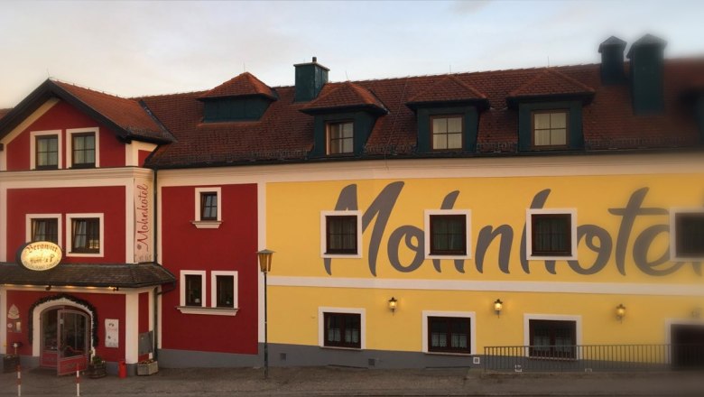 Facade of the Bergwirt Schrammel & Mohnhotel with red and yellow paint.