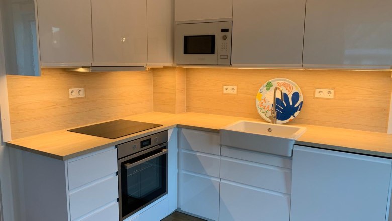 Modern kitchen with white cupboards, wooden worktop, built-in oven and sink.