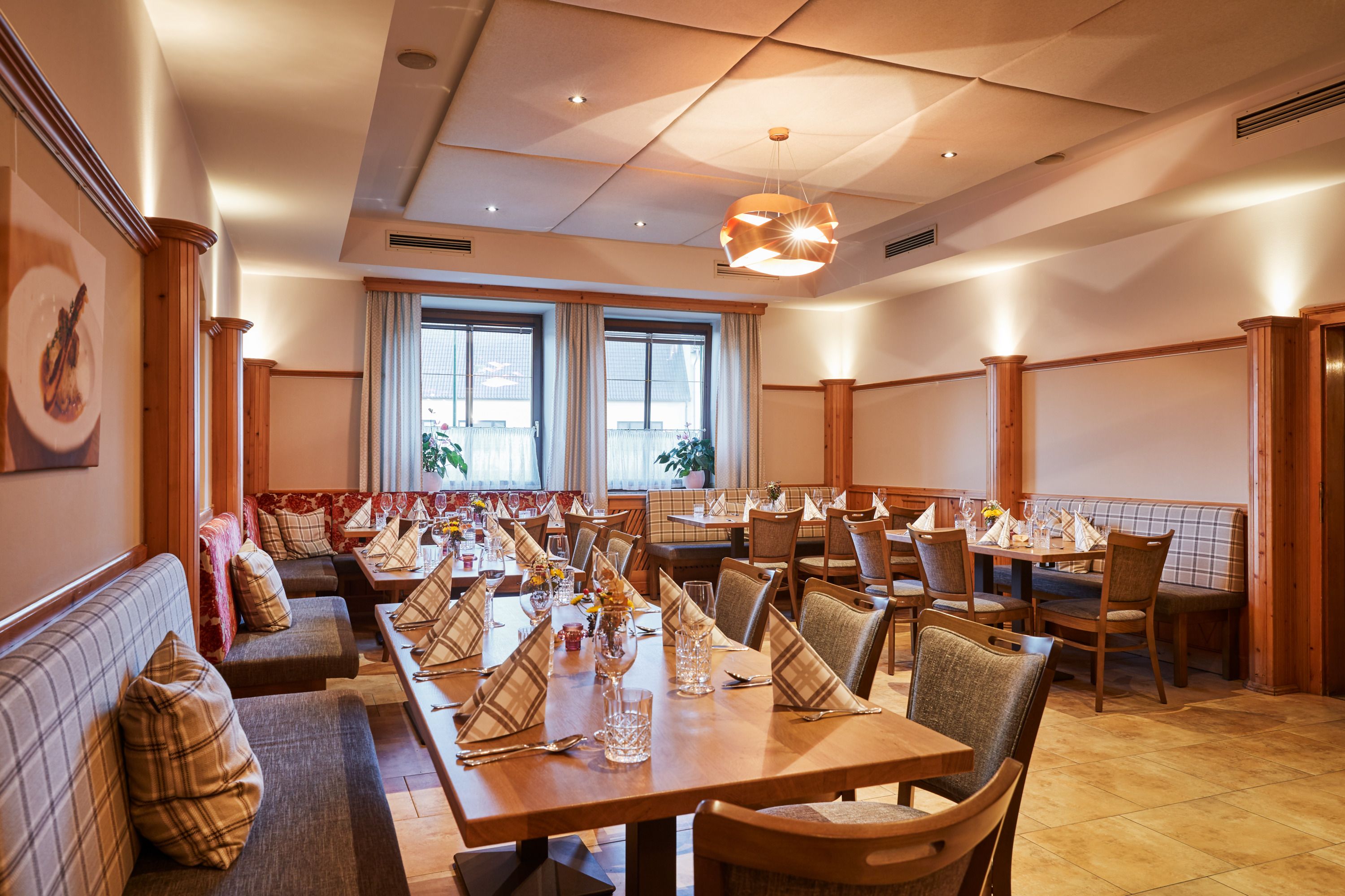 Cozy dining room with laid tables and wood paneling.
