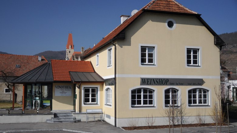 Yellow building with the inscription 'Weinshop' and 'Vinothek' in a rural setting.