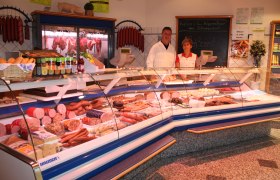 Two people behind a meat counter in a butcher's shop.