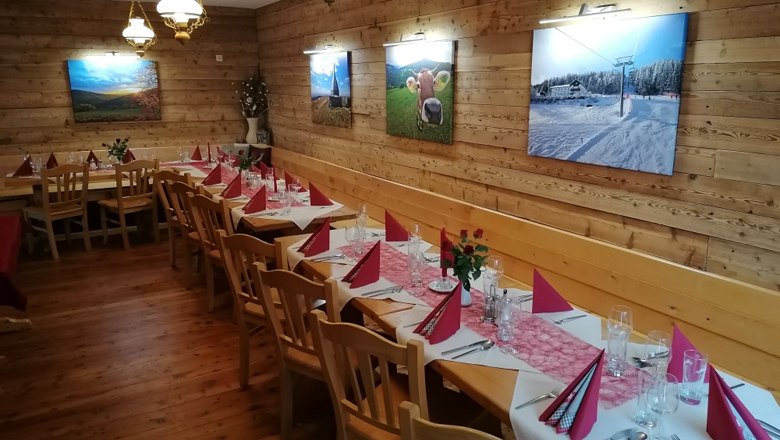 A festively decorated hall with wooden walls, decorated with pictures and red napkins on the tables.
