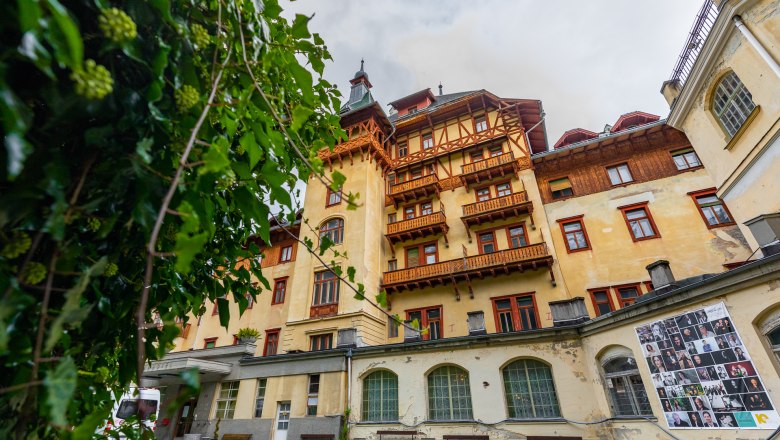 Historic building of the Südbahnhotel Semmering with wooden decorations and balconies, surrounded by green plants.