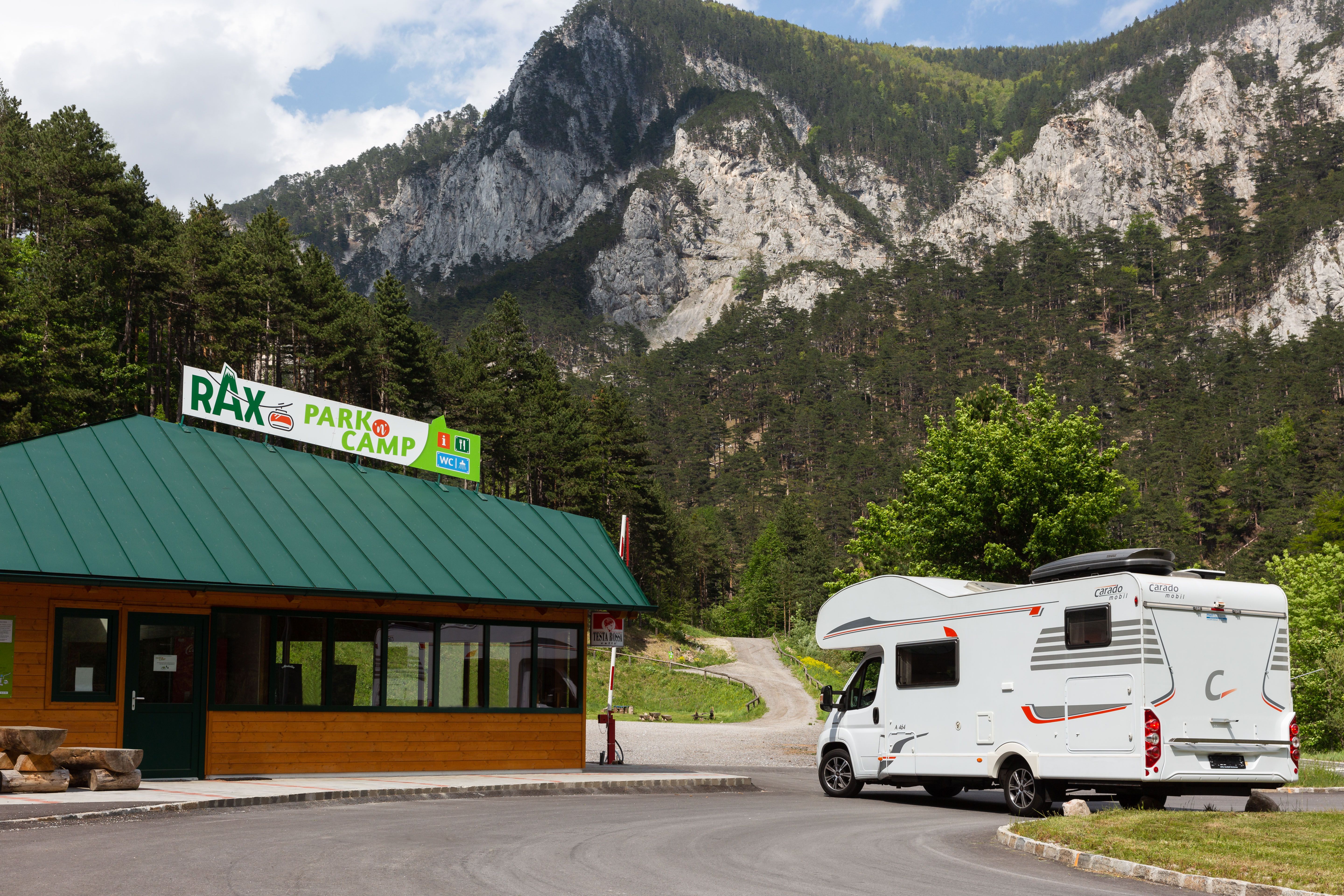 Motorhome in front of the Rax Park'n'Camp building with mountain backdrop.