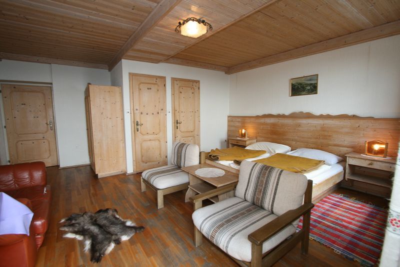 Cozy double room with wooden furniture, double bed, armchairs and carpet.