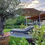 Garden with sun lounger, parasol and olive tree in front of a modern chalet.