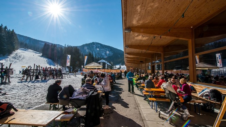 People sitting outside a restaurant in a ski resort.
