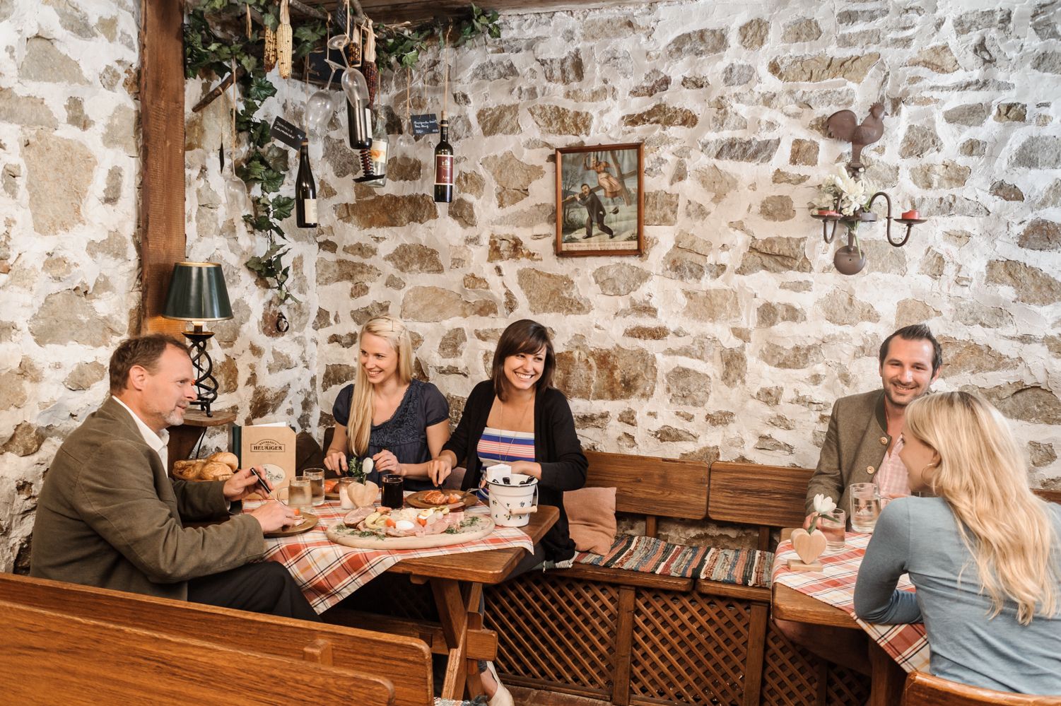 Group of people in a traditional wine tavern with stone walls, food and wine.