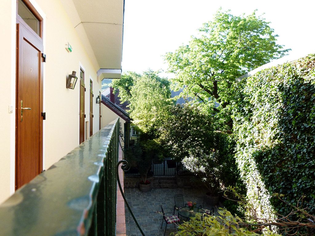 View from a balcony onto a green inner courtyard with trees and climbing plants.