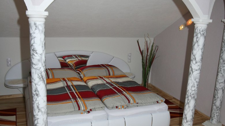 Bedroom with double bed, marble pillars and striped bed linen.
