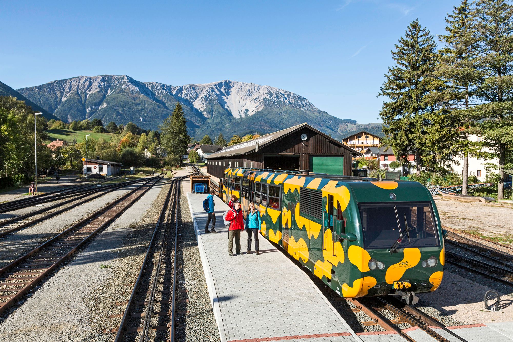 Railroad station in Puchberg am Schneeberg with a colorful rack railroad in the foreground and mountains in the background.