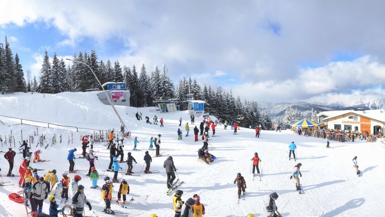 Ski area with lots of people, chair lift and mountain landscape.