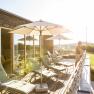 Sunny roof terrace with sun loungers and parasols, with a view of the countryside.