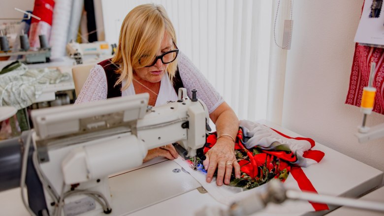 A woman sews on a sewing machine in a workshop.